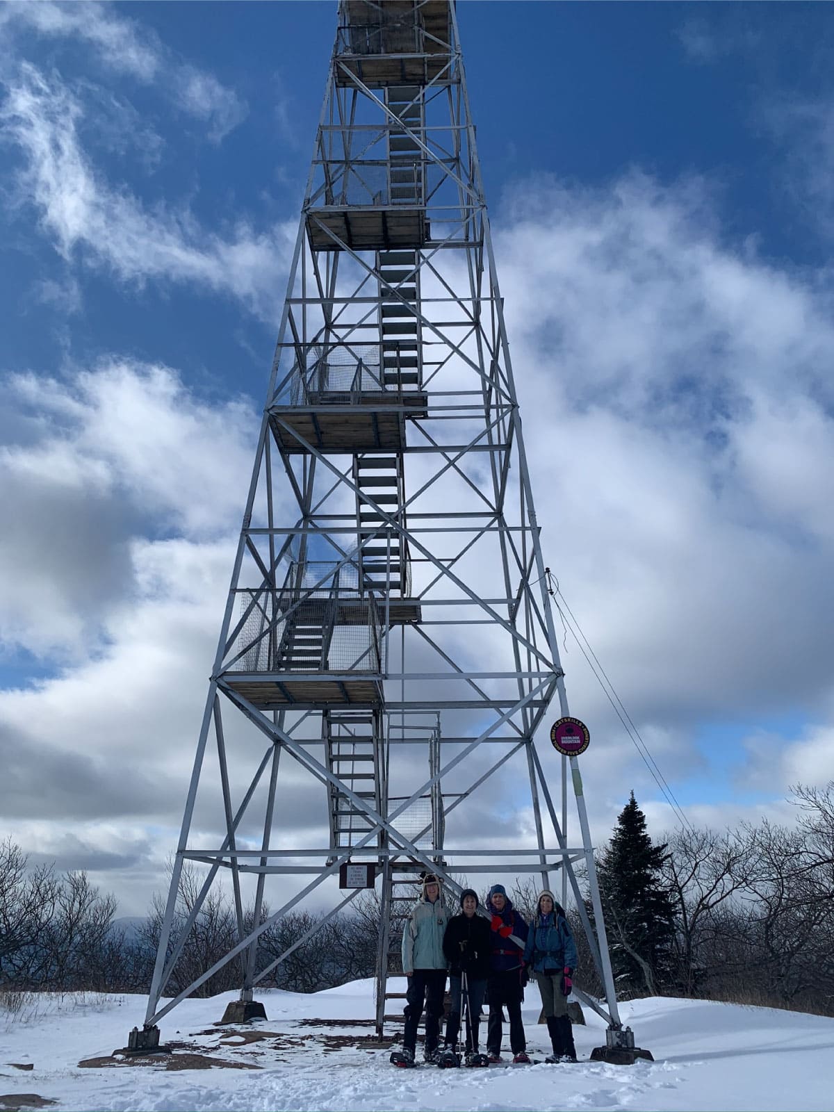 Hikers stand in front of a fire tower