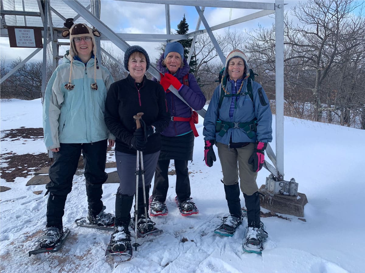 Snowshoers pause at a summit tower